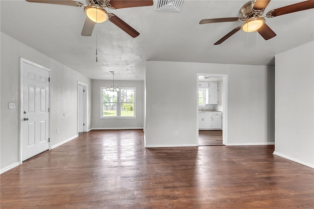 130 N Houston St, Aransas Pass, TX 78336 - unfurnished living room featuring ceiling fan with notable chandelier, baseboards, visible vents, and dark wood-style flooring