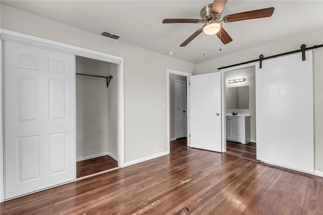 130 N Houston St, Aransas Pass, TX 78336 - unfurnished bedroom featuring a barn door, wood-type flooring, a closet, and baseboards