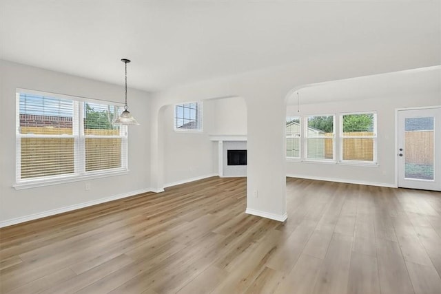 7821 Kingshire Dr, Corpus Christi, TX 78413 - unfurnished living room with wood finished floors, a fireplace, and arched walkways