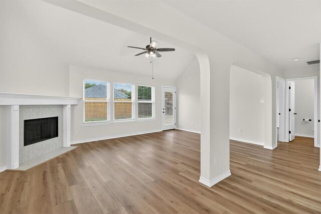 7821 Kingshire Dr, Corpus Christi, TX 78413 - unfurnished living room featuring a ceiling fan, wood finished floors, a tiled fireplace, and vaulted ceiling