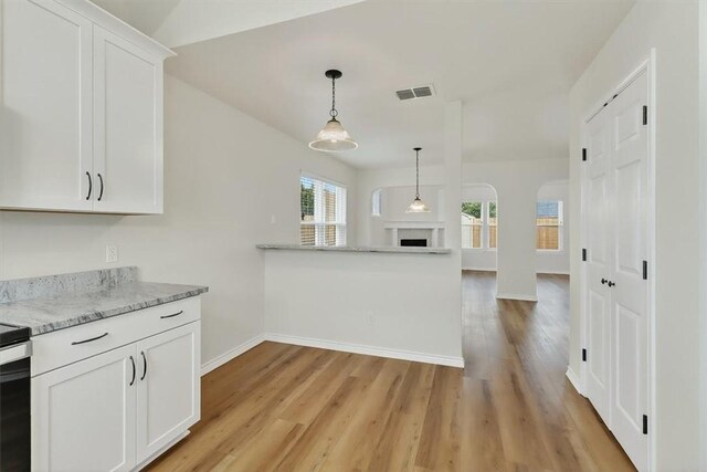 7821 Kingshire Dr, Corpus Christi, TX 78413 - kitchen with light wood-type flooring, white cabinets, pendant lighting, light stone counters, and open floor plan