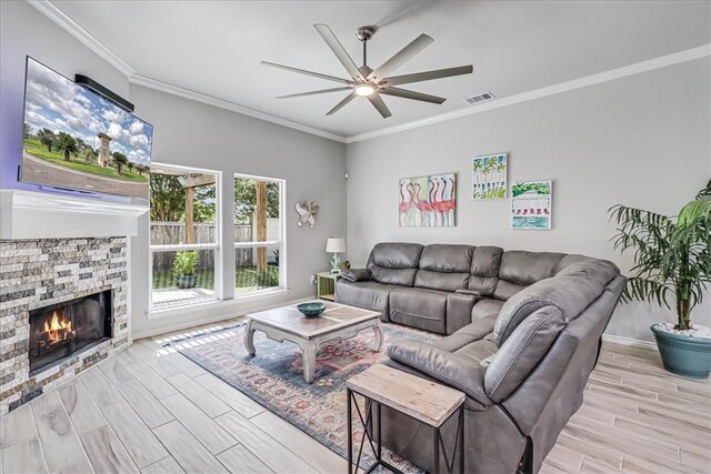 living room with ornamental molding, a fireplace, light hardwood / wood-style flooring, and ceiling fan