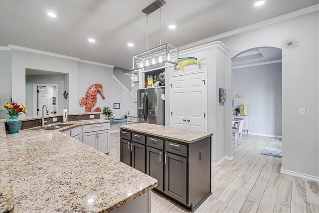 kitchen featuring light stone countertops, stainless steel fridge, decorative light fixtures, and a kitchen island