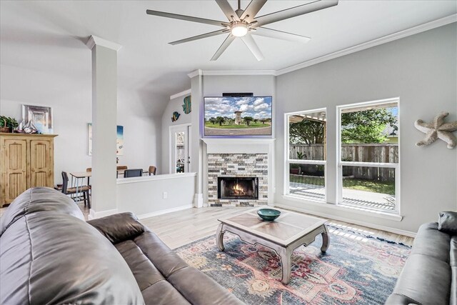 living room featuring a stone fireplace, hardwood / wood-style flooring, ceiling fan, and crown molding