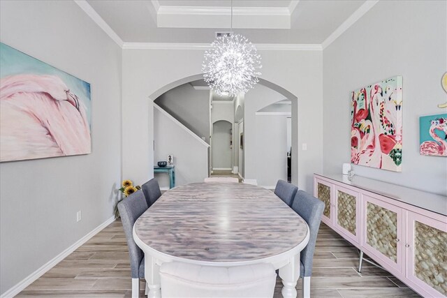 dining room with a chandelier, a tray ceiling, light hardwood / wood-style floors, and crown molding