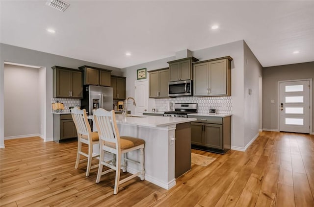 7602 Bayley Ln, Corpus Christi, TX 78414 - kitchen with stainless steel appliances, backsplash, a sink, a breakfast bar, and a kitchen island with sink