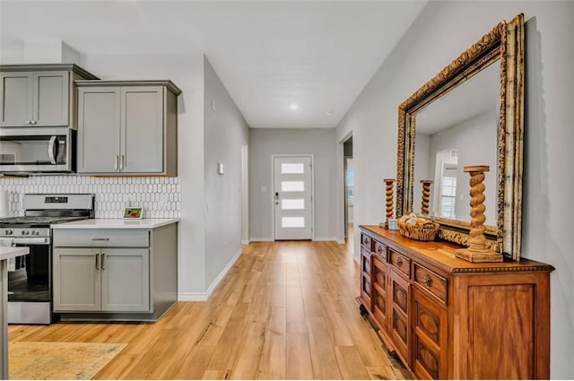 7602 Bayley Ln, Corpus Christi, TX 78414 - kitchen featuring stainless steel appliances, gray cabinetry, light wood finished floors, tasteful backsplash, and baseboards