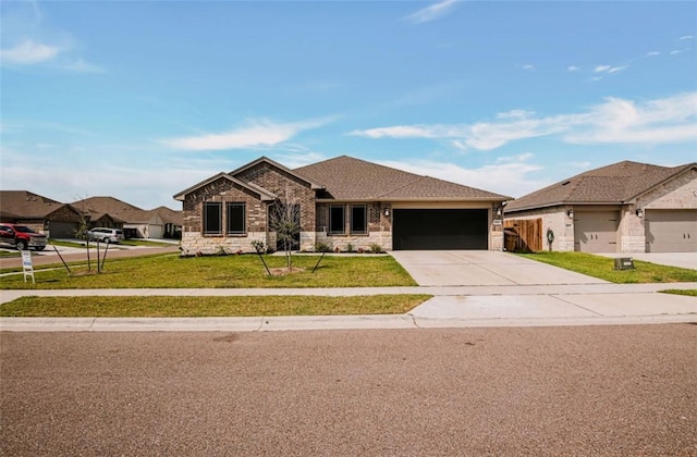 7602 Bayley Ln, Corpus Christi, TX 78414 - view of front facade featuring concrete driveway, an attached garage, a front lawn, and stone siding