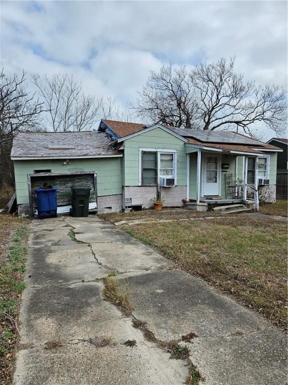 ranch-style home with cooling unit, covered porch, and solar panels