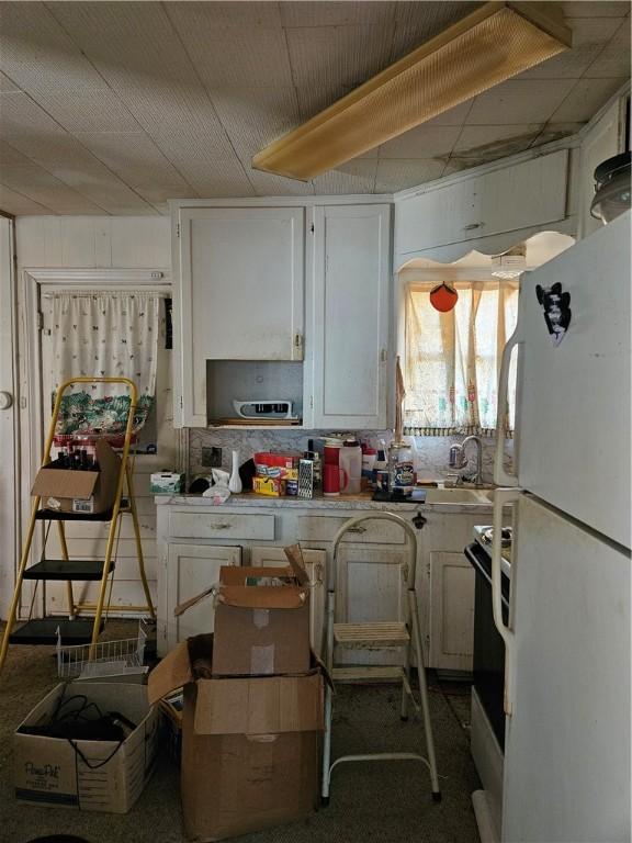 kitchen featuring white cabinetry, white fridge, sink, and electric range