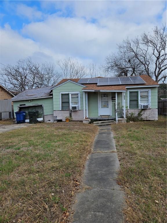 ranch-style home with cooling unit, a front yard, and solar panels