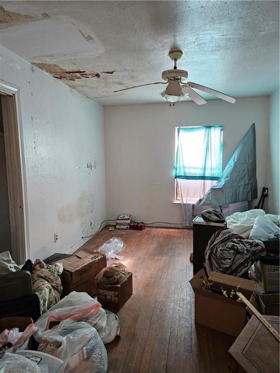 bedroom with ceiling fan, wood-type flooring, and a textured ceiling