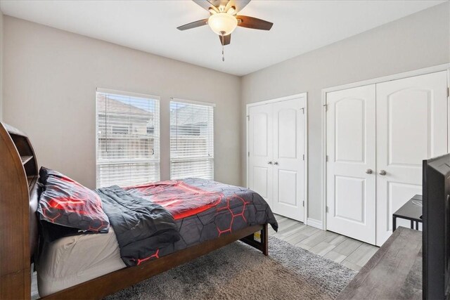 bedroom with ceiling fan, two closets, and light hardwood / wood-style flooring