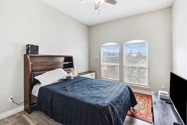 bedroom featuring ceiling fan, light hardwood / wood-style floors, and multiple windows