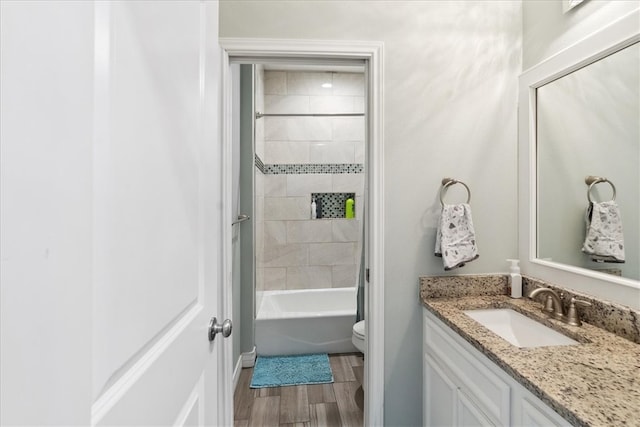 full bathroom with toilet, vanity, tiled shower / bath, and hardwood / wood-style flooring