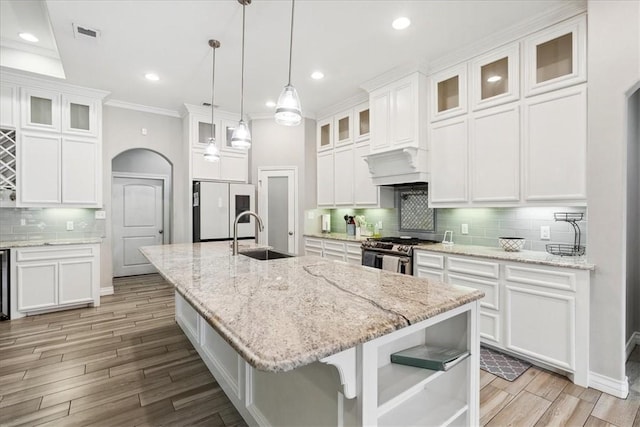 kitchen featuring stainless steel gas range oven, fridge, sink, and white cabinetry