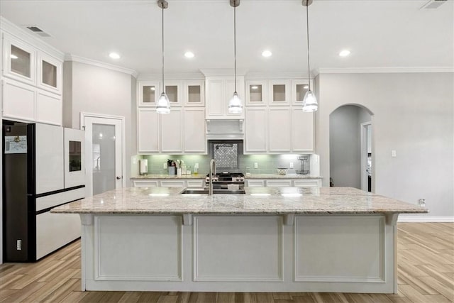 kitchen with decorative light fixtures, white cabinets, and an island with sink