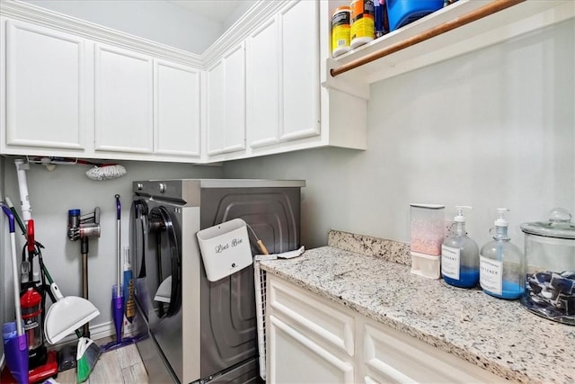 clothes washing area featuring cabinets, washer and clothes dryer, and light wood-type flooring