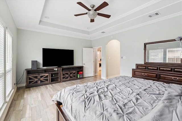 bedroom featuring ceiling fan, a tray ceiling, ornamental molding, and light hardwood / wood-style floors