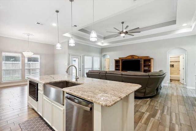 kitchen with pendant lighting, stainless steel dishwasher, and a tray ceiling