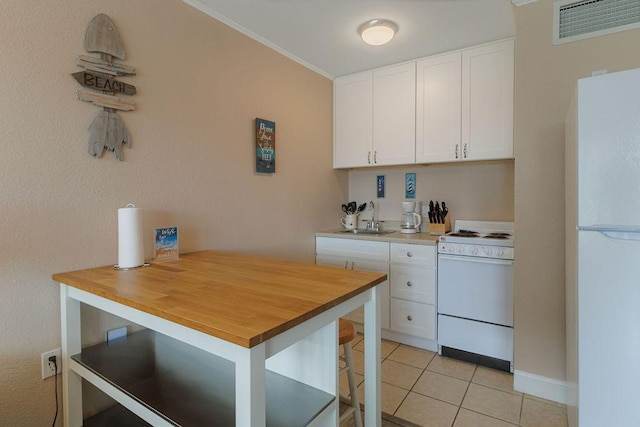 kitchen featuring white cabinetry, sink, white appliances, and light tile patterned floors