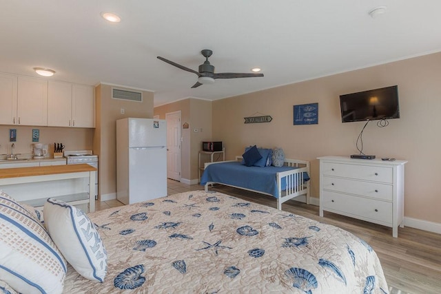 bedroom with white refrigerator, ceiling fan, sink, and light wood-type flooring