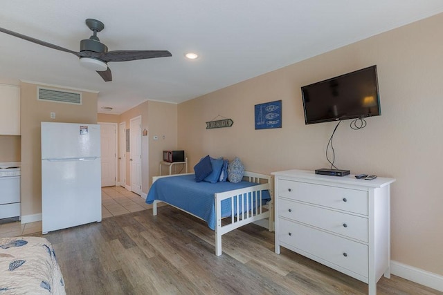 bedroom with white refrigerator, ceiling fan, and light wood-type flooring