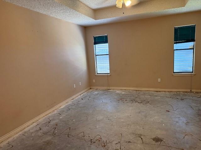 6026 Blue Water Dr, Corpus Christi, TX 78415 - unfurnished room featuring a tray ceiling, a textured ceiling, a ceiling fan, and baseboards