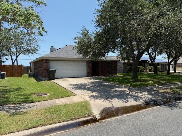 6026 Blue Water Dr, Corpus Christi, TX 78415 - ranch-style home featuring a garage, concrete driveway, cooling unit, brick siding, and a chimney