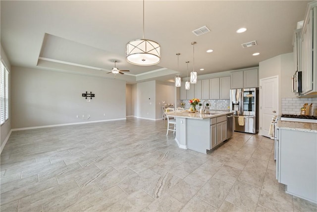 2538 Las Estrellas St, Corpus Christi, TX 78414 - kitchen with stainless steel appliances, gray cabinets, a raised ceiling, tasteful backsplash, and open floor plan