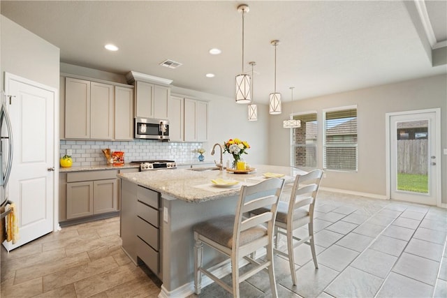 2538 Las Estrellas St, Corpus Christi, TX 78414 - kitchen with stainless steel microwave, tasteful backsplash, a sink, a breakfast bar area, and a center island with sink