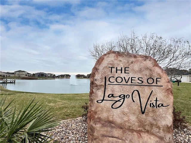 community sign with a water view and a yard