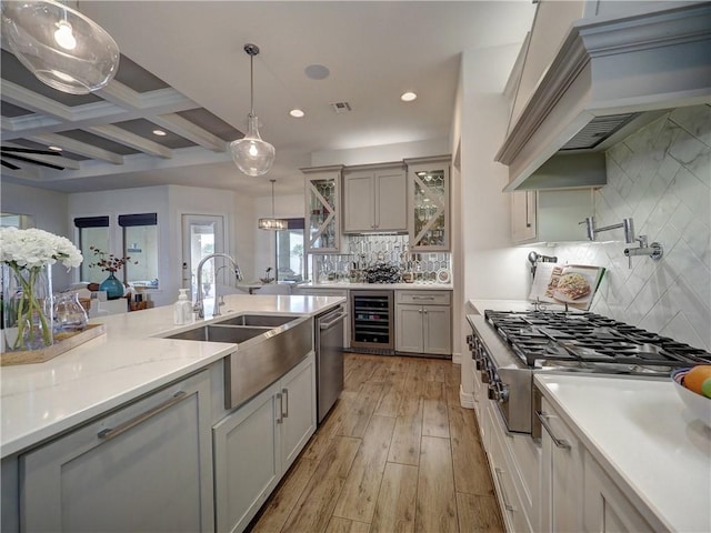 kitchen with beverage cooler, glass insert cabinets, custom exhaust hood, pendant lighting, and a sink