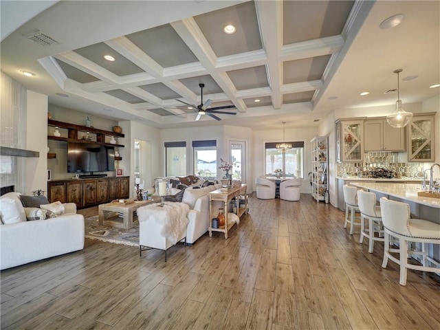 living room featuring light wood-style floors, visible vents, coffered ceiling, and beamed ceiling