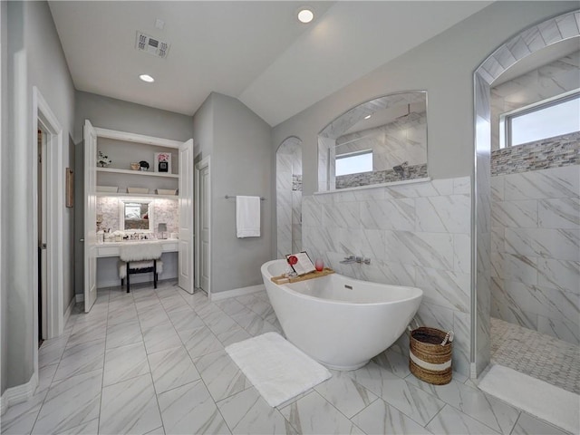 bathroom featuring plenty of natural light, marble finish floor, a soaking tub, and recessed lighting