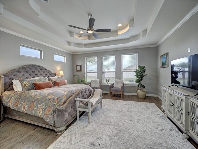 bedroom featuring a raised ceiling, crown molding, baseboards, and wood finished floors