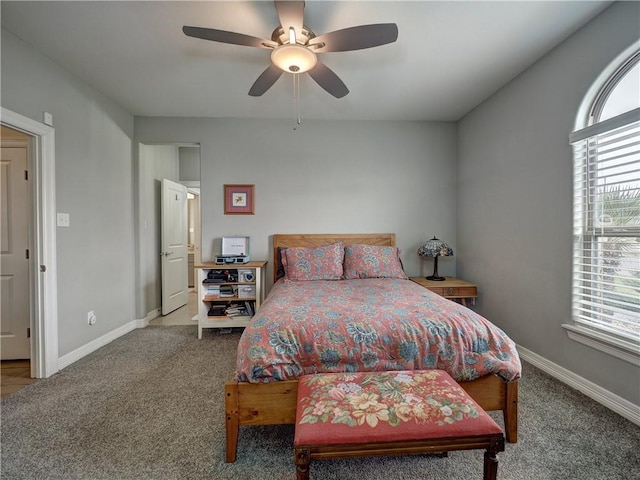 carpeted bedroom with a ceiling fan, multiple windows, and baseboards