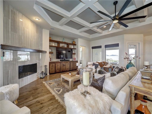 living room featuring beam ceiling, coffered ceiling, a fireplace, and wood finished floors