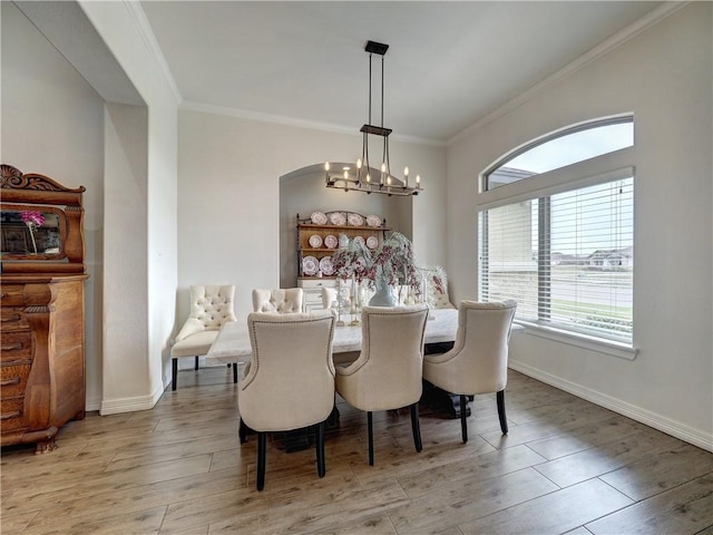 dining area featuring baseboards, light wood-type flooring, and crown molding