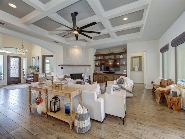 living room featuring light wood-type flooring, coffered ceiling, and beamed ceiling