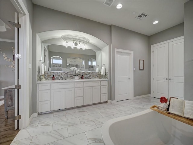 full bathroom featuring marble finish floor, a freestanding tub, vanity, and visible vents