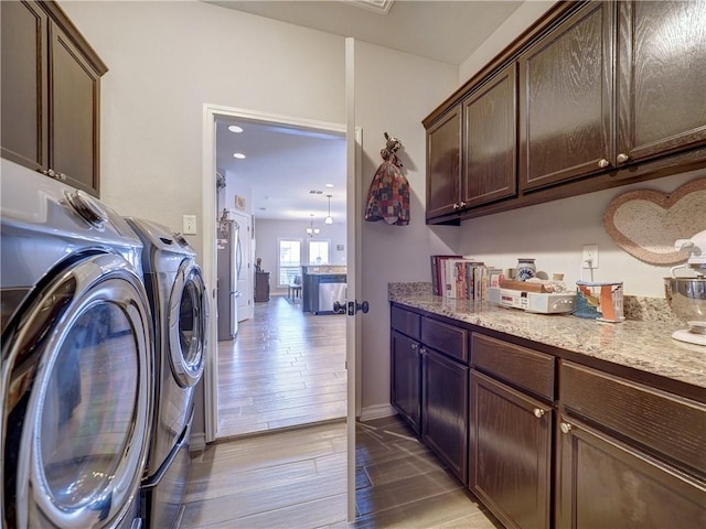 clothes washing area featuring washer and dryer and cabinets