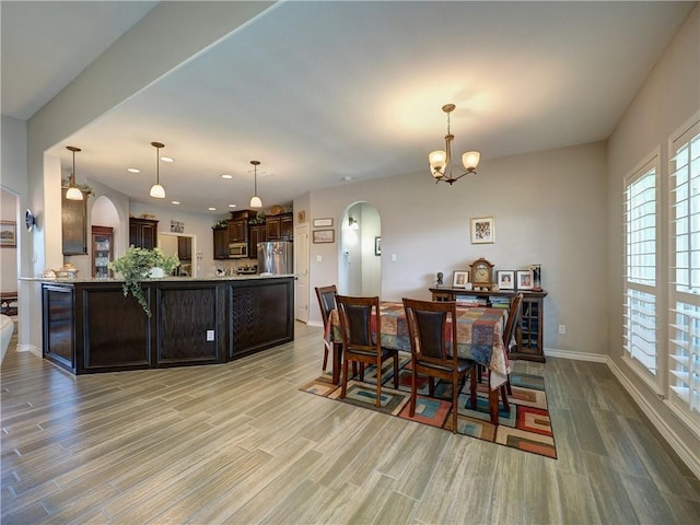 dining room with light wood-type flooring and an inviting chandelier