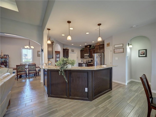 kitchen featuring light stone countertops, hanging light fixtures, stainless steel appliances, a notable chandelier, and dark brown cabinets