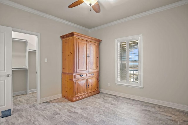 unfurnished bedroom with a walk in closet, crown molding, ceiling fan, light hardwood / wood-style floors, and a closet