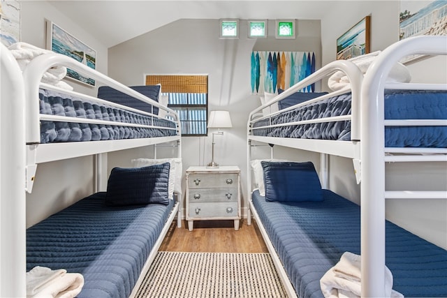 bedroom featuring multiple windows, hardwood / wood-style floors, and lofted ceiling