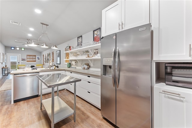 kitchen featuring light hardwood / wood-style floors, white cabinets, kitchen peninsula, hanging light fixtures, and appliances with stainless steel finishes