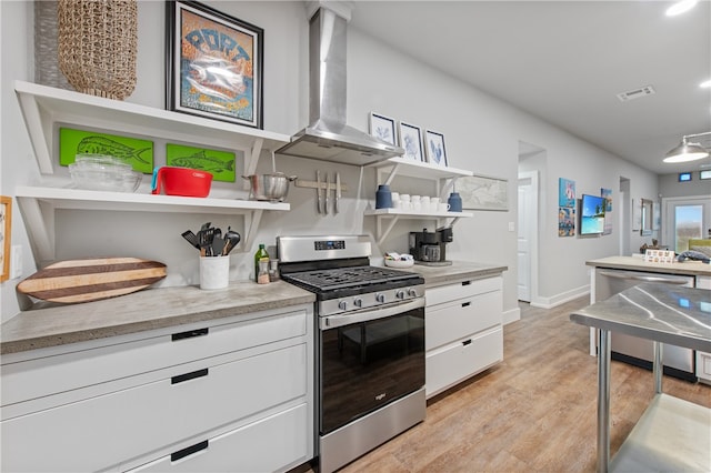 kitchen with wall chimney range hood, white cabinetry, light hardwood / wood-style flooring, and appliances with stainless steel finishes