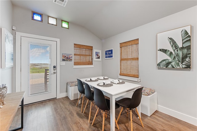 dining area featuring hardwood / wood-style floors and vaulted ceiling