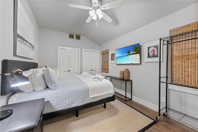 bedroom featuring hardwood / wood-style flooring, multiple closets, ceiling fan, and vaulted ceiling